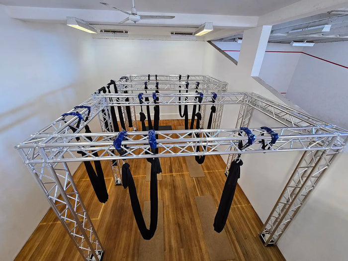 A disused squash court in Geraldton (WA) turned it into an aerial yoga studio. Aerial yoga hammocks suspend from carabiners and slings off a heavy duty Titan AV 290 box truss frame.